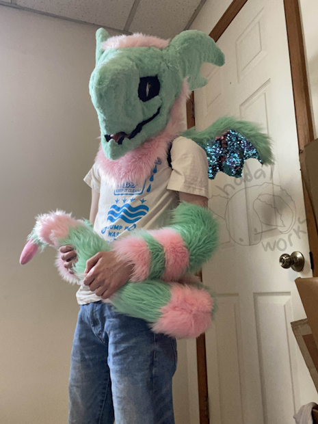 Photo of the suit being worn. I am leaning back and holding the tail in my hands. I'm missing the hand paws. You can see a small fleece heart hanging off the tail tip.