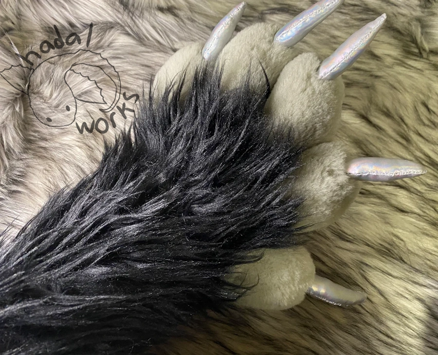 A look at the back of the paw's hands, showing the short gray fur of the toes contrast against the long black fur of the arms.