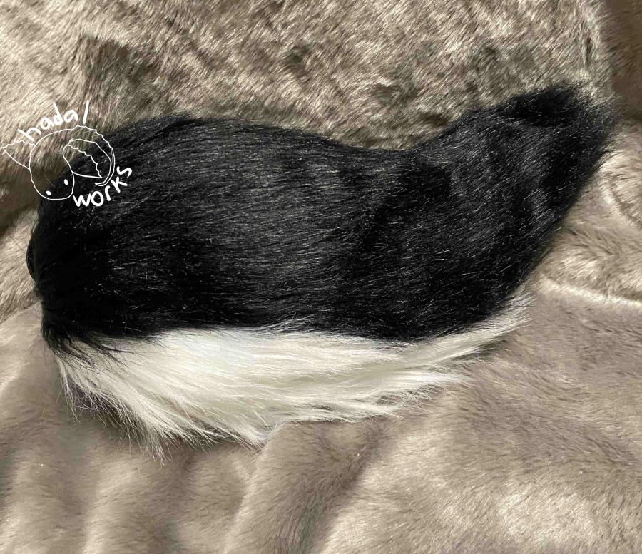 Short fursuit tail with a black top and white underside.